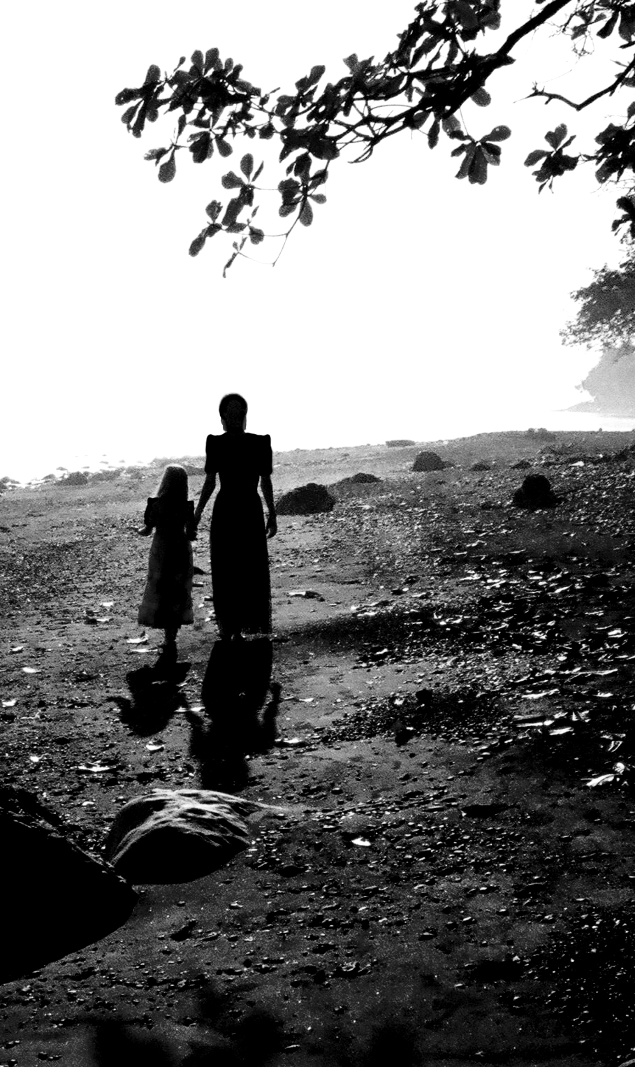 A woman and a girl walking together on a dirt road