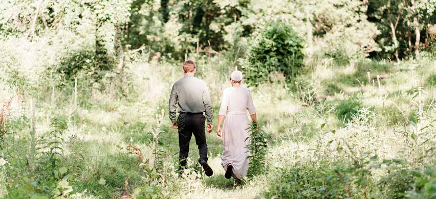 ’n Man en vrou wat saam deur ’n groen weiding stap