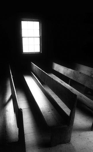 Sunlight falls through a chapel window onto wooden pews