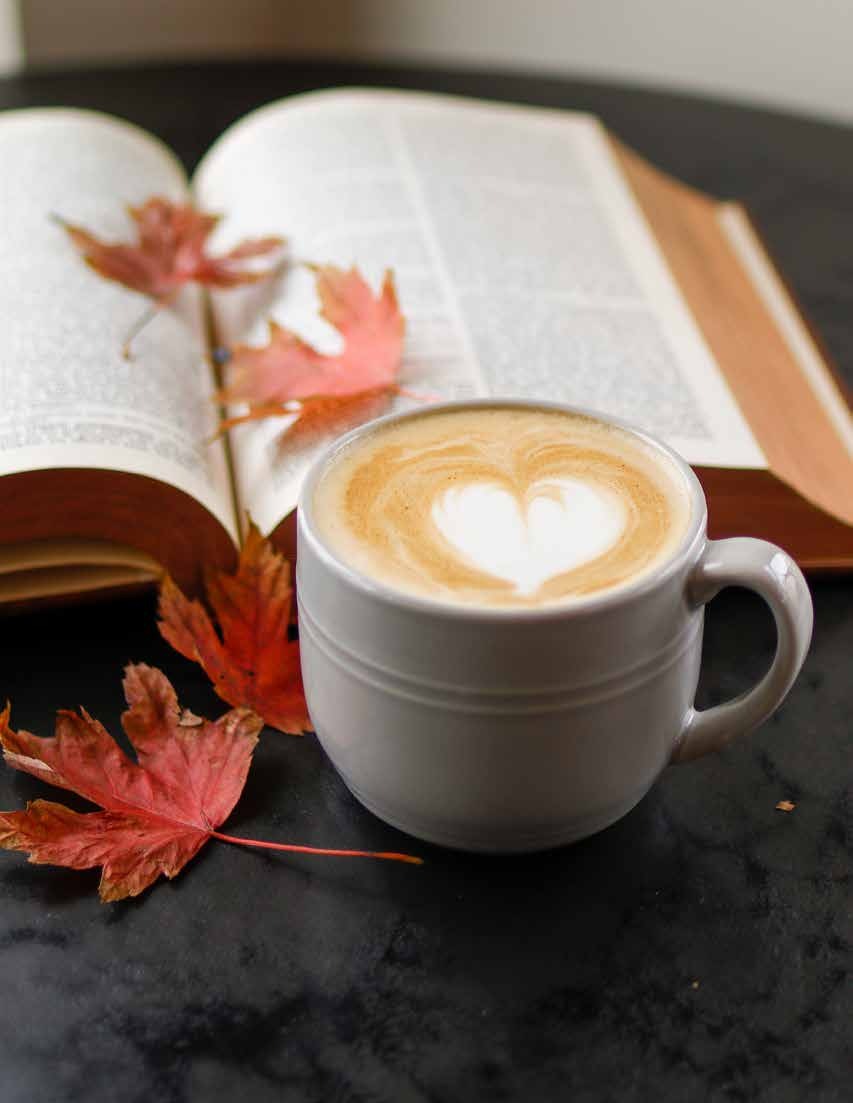 An open Bible beside a cup of coffee and autumn leaves