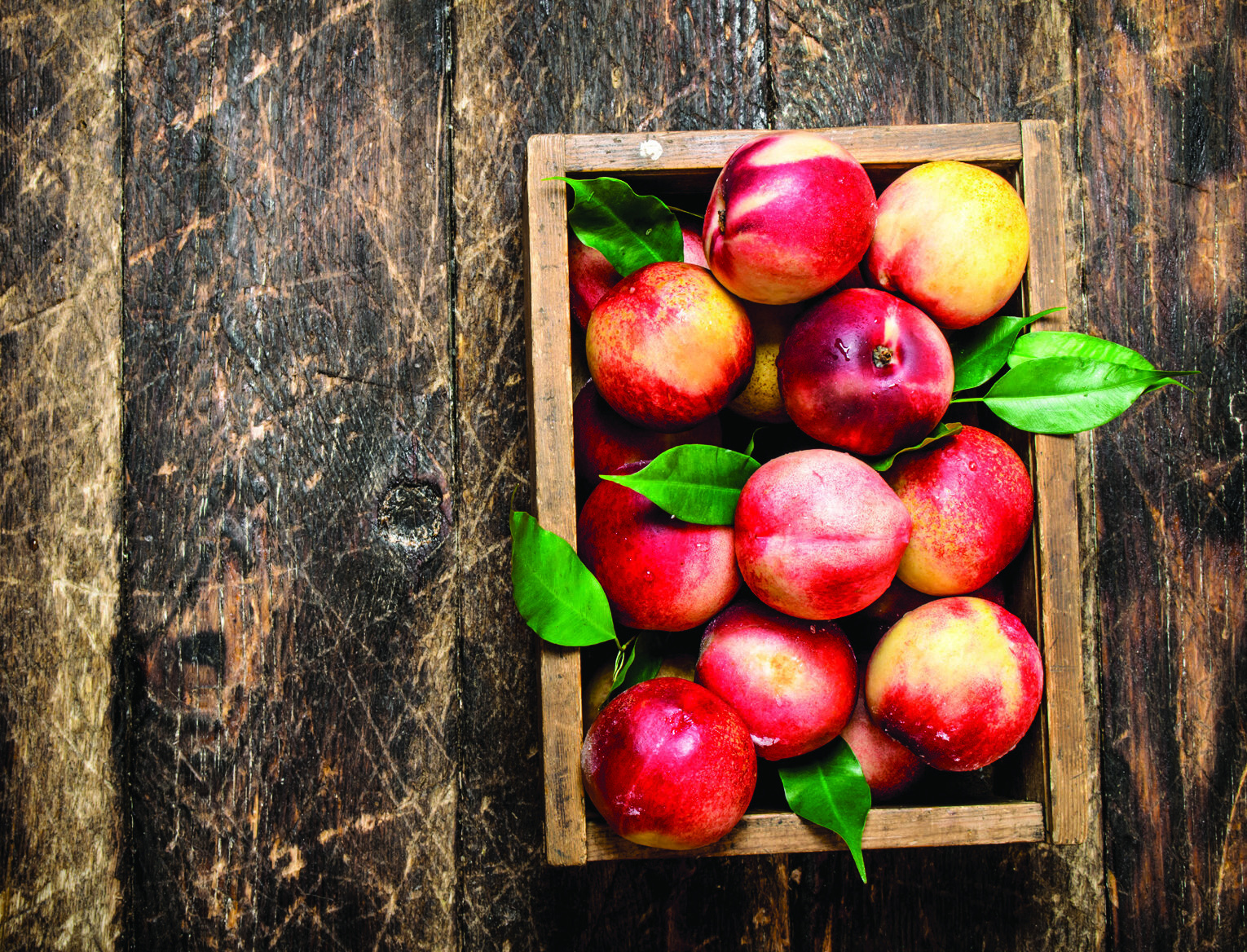 A crate of peaches on weathered wood
