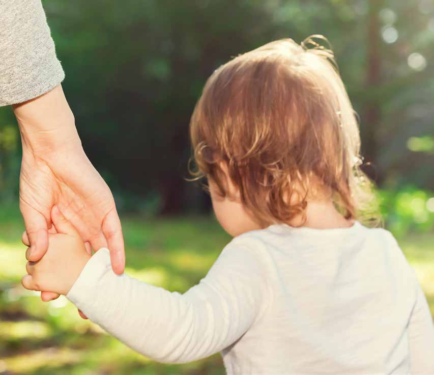 Adult holding the hand of a small child walking outdoors