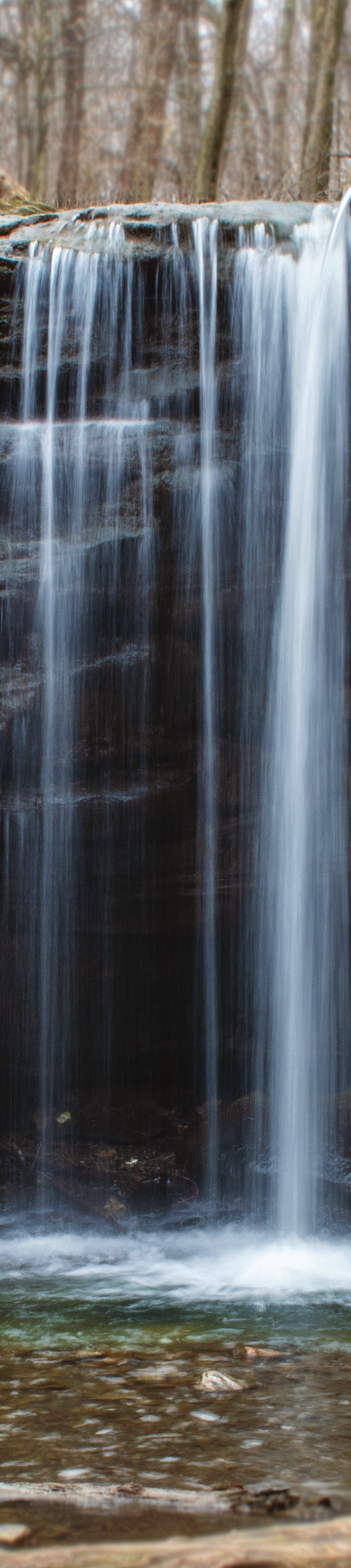 A waterfall flowing over layered rock ledges in a forest