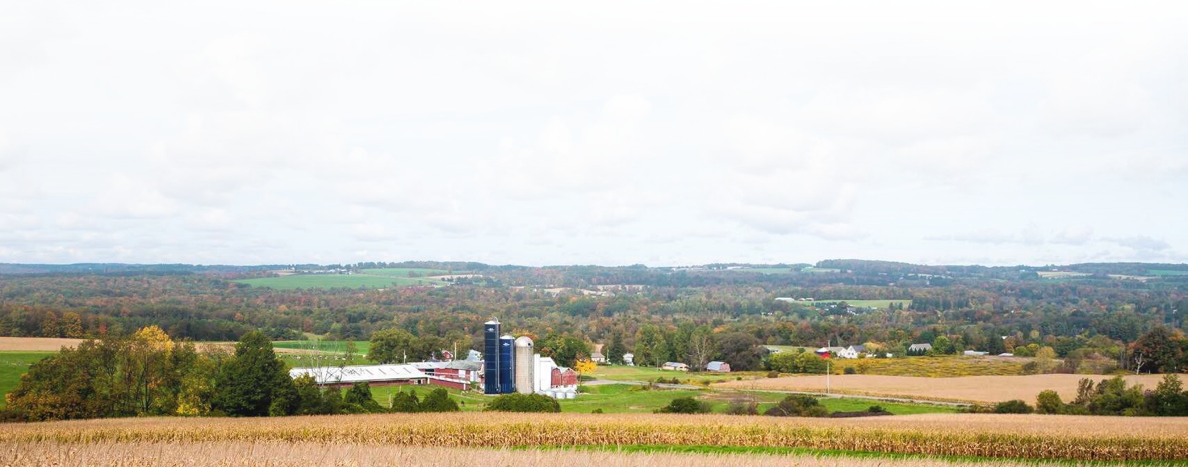 Farm fields and buildings across a rolling rural valley in autumn