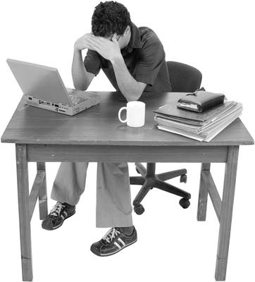 A man sitting at a computer with his head in his hands