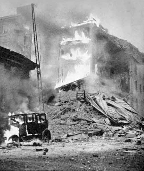 Burning vehicle and damaged building amid rubble