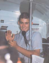A young man holding a microphone on a bus.