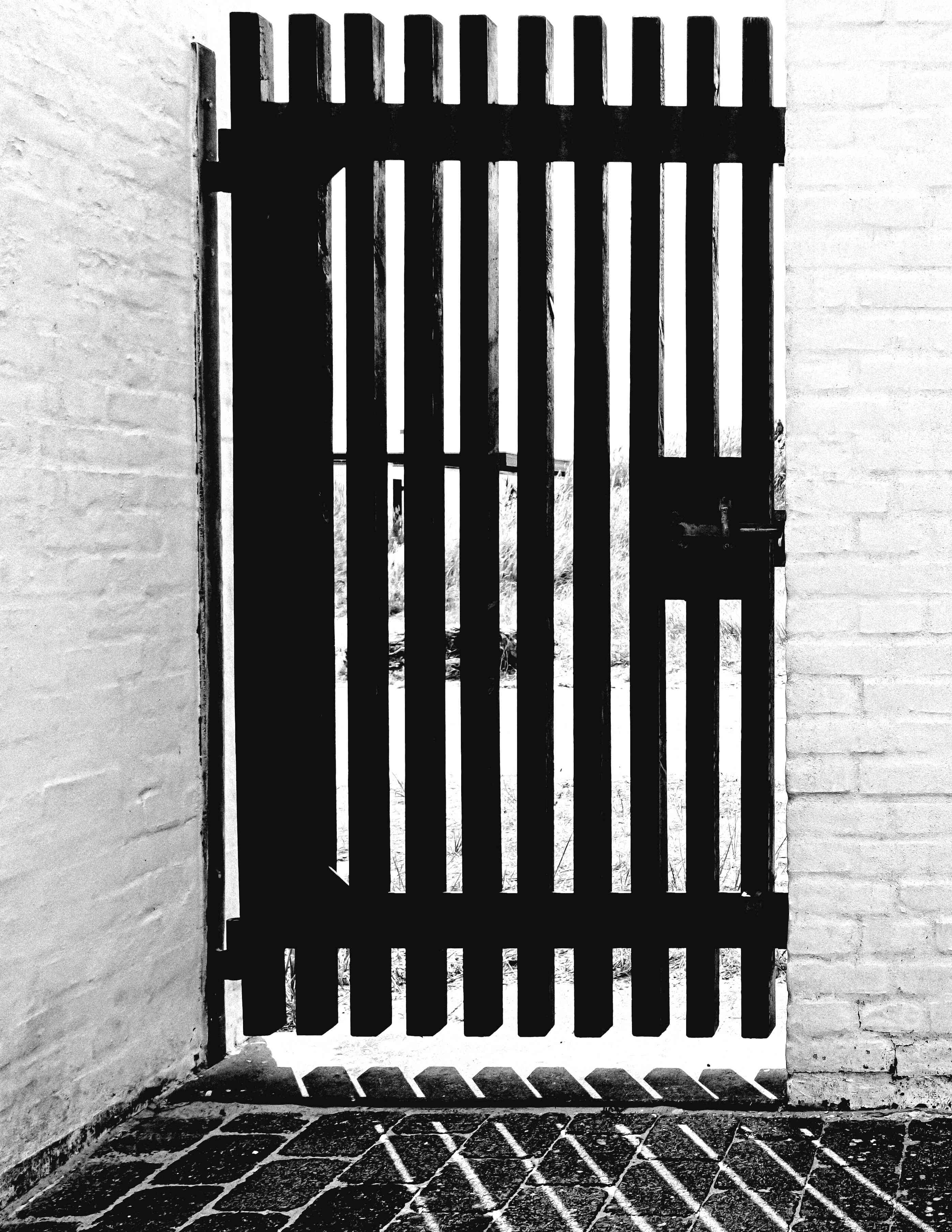 A narrow wooden gate between white walls