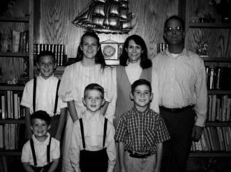 A family of seven standing together in front of bookshelves.
