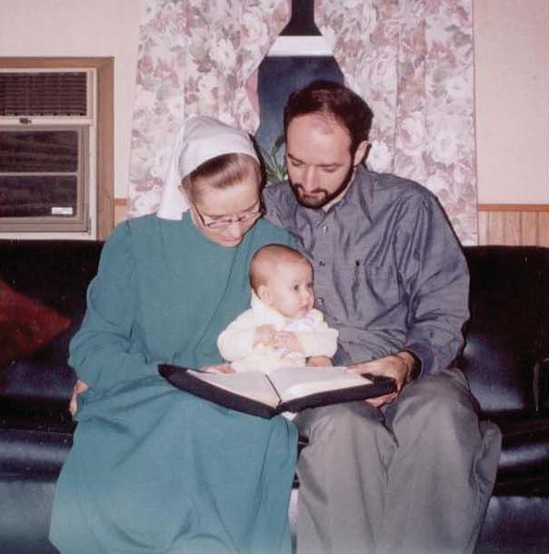 A couple with an infant reading an open book