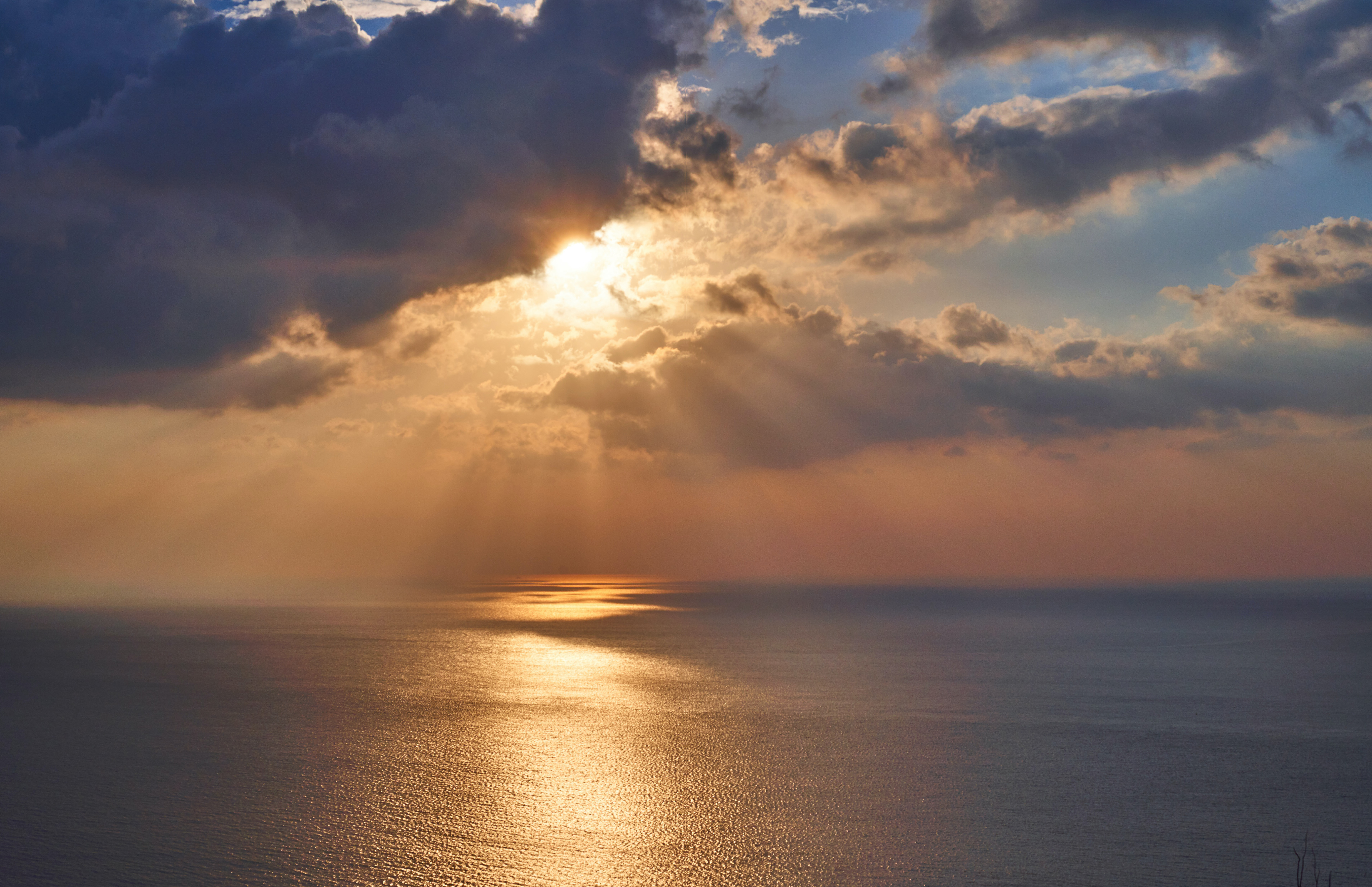 Sunlight breaking through clouds over a calm ocean