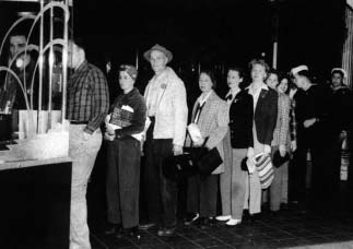 People standing in a queue beside a ticket counter