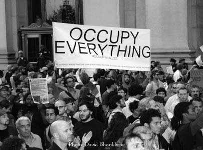A crowd at an Occupy protest holding a sign that reads ‘OCCUPY EVERYTHING’