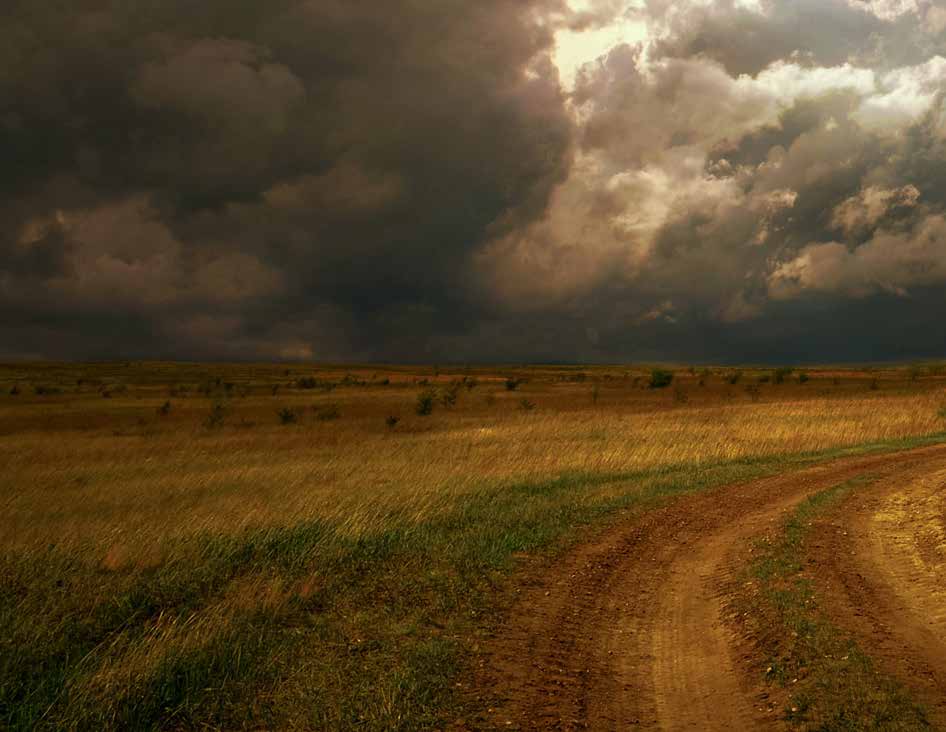 Storm clouds over a prairie road, left half of a two-page photograph