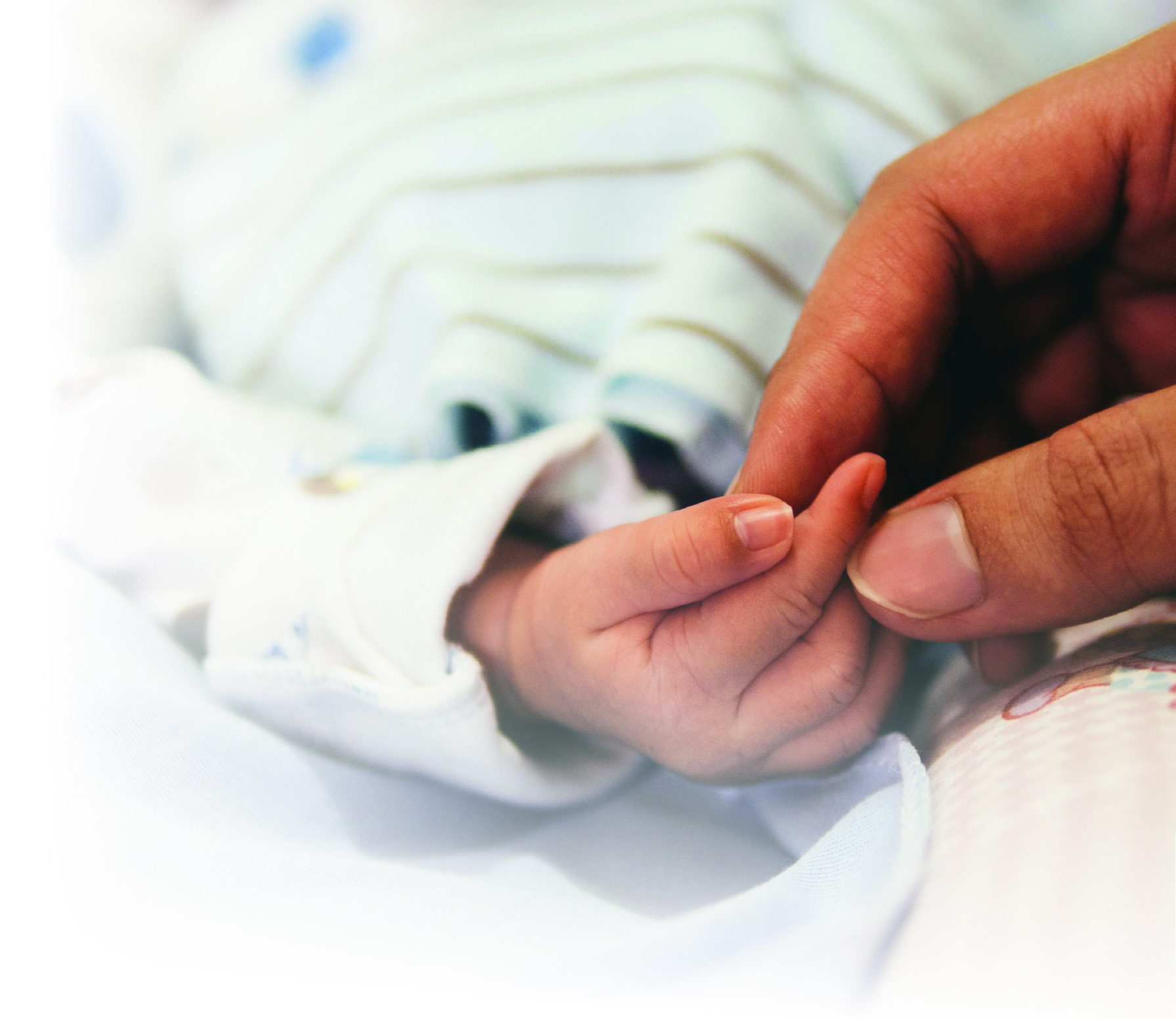 A newborn baby’s hand holding an adult’s finger