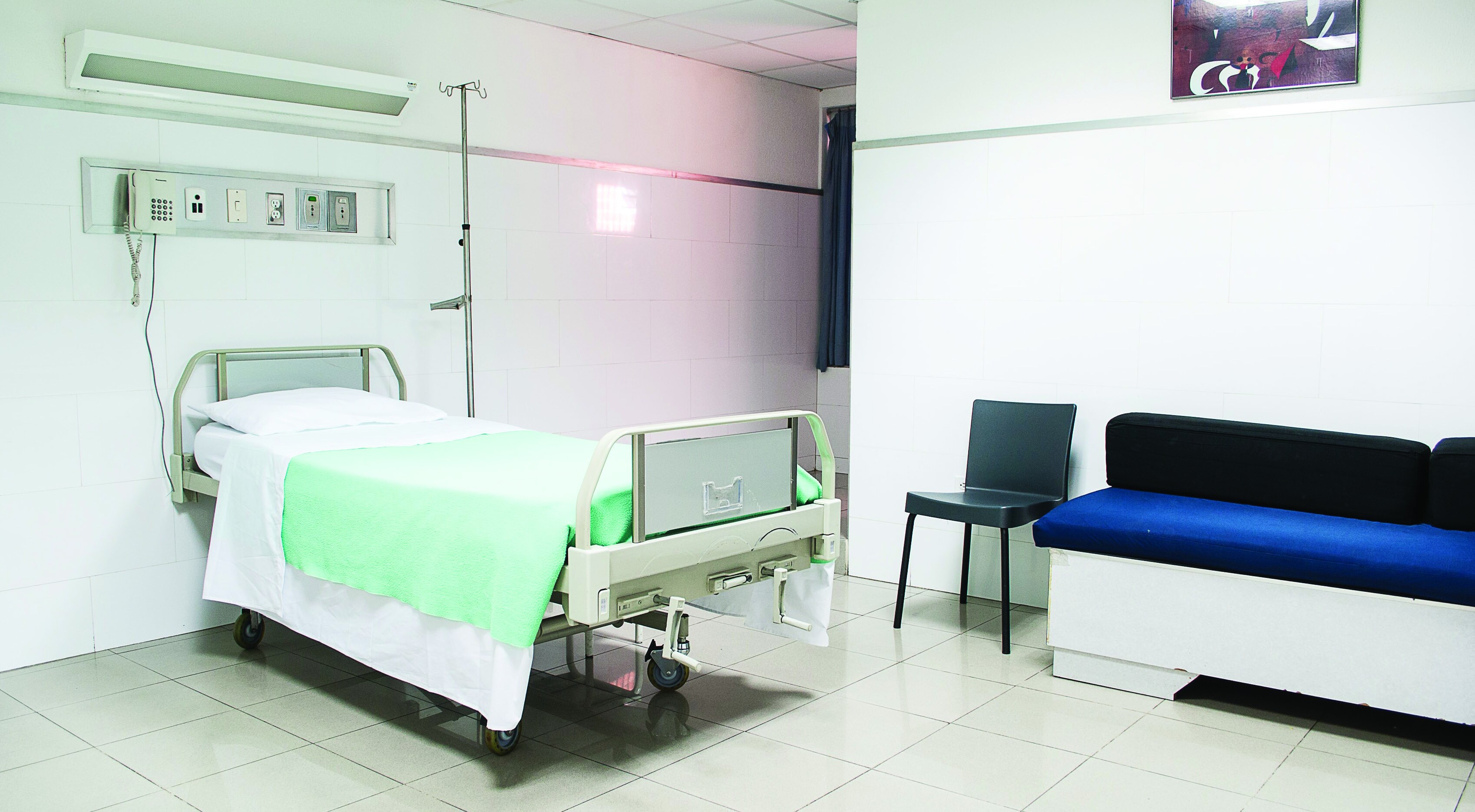 An empty hospital room with a bed and seating