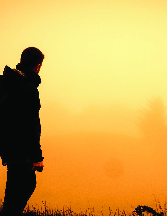 A person standing against a golden sky