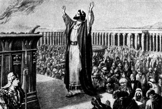 A robed man raises both arms before a large assembly in a courtyard