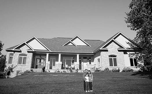 A large house with a family standing on the front lawn