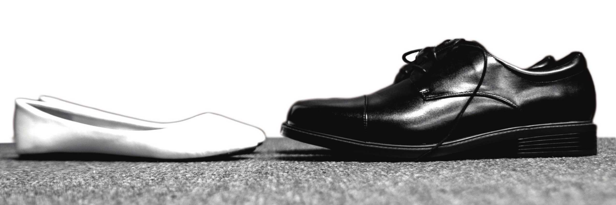 A white women’s shoe and a black men’s shoe side by side