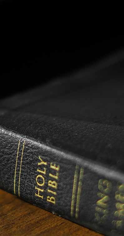 A black Holy Bible on a dark wooden surface