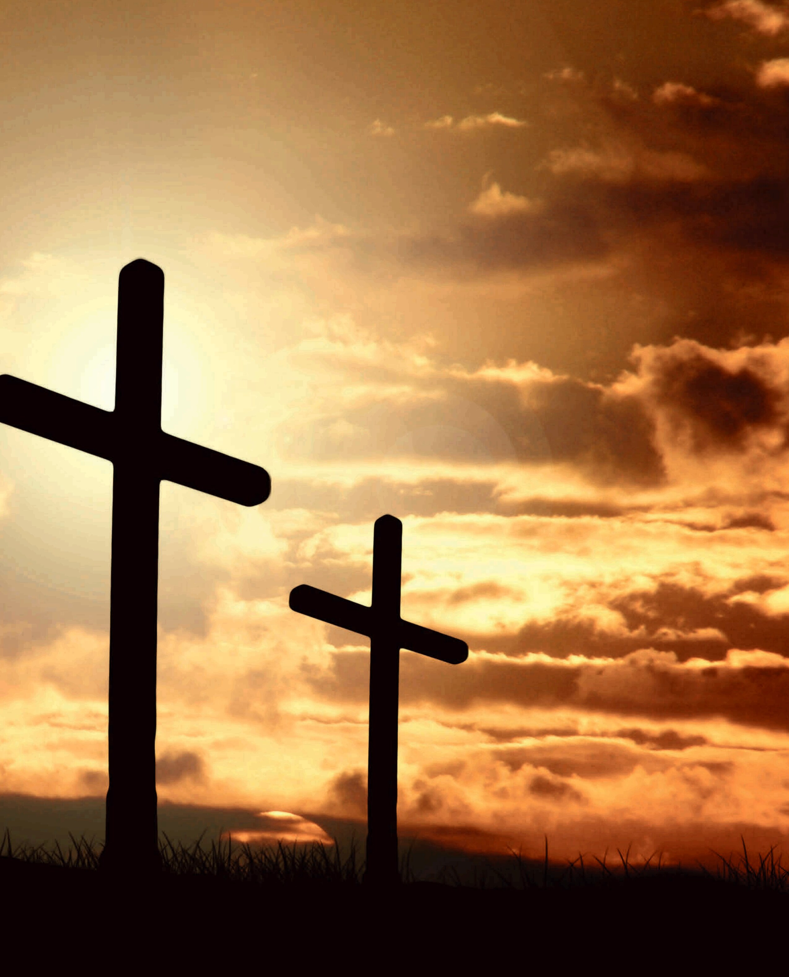 Two cross silhouettes against sunset clouds