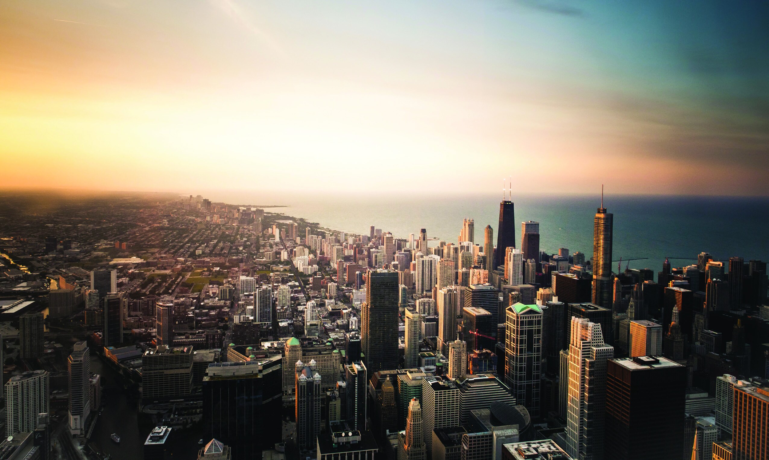 Aerial view of a city skyline beside a lake at sunset