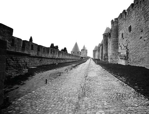 A cobblestone road between stone fortress walls