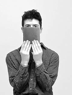 Man holding a book in front of his mouth