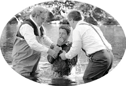 Two men baptizing a person in water