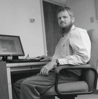 portrait of a bearded man seated at a desk