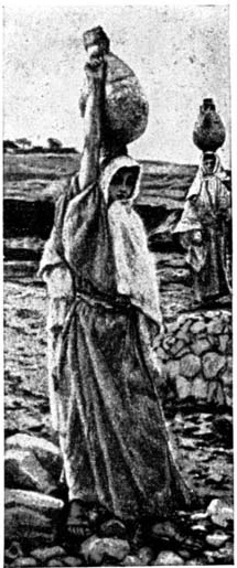 A woman carries a vessel on her head along a rocky path