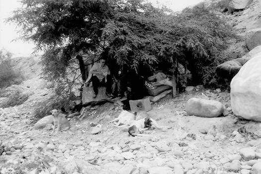 Children beneath a shelter beside a rocky riverbank