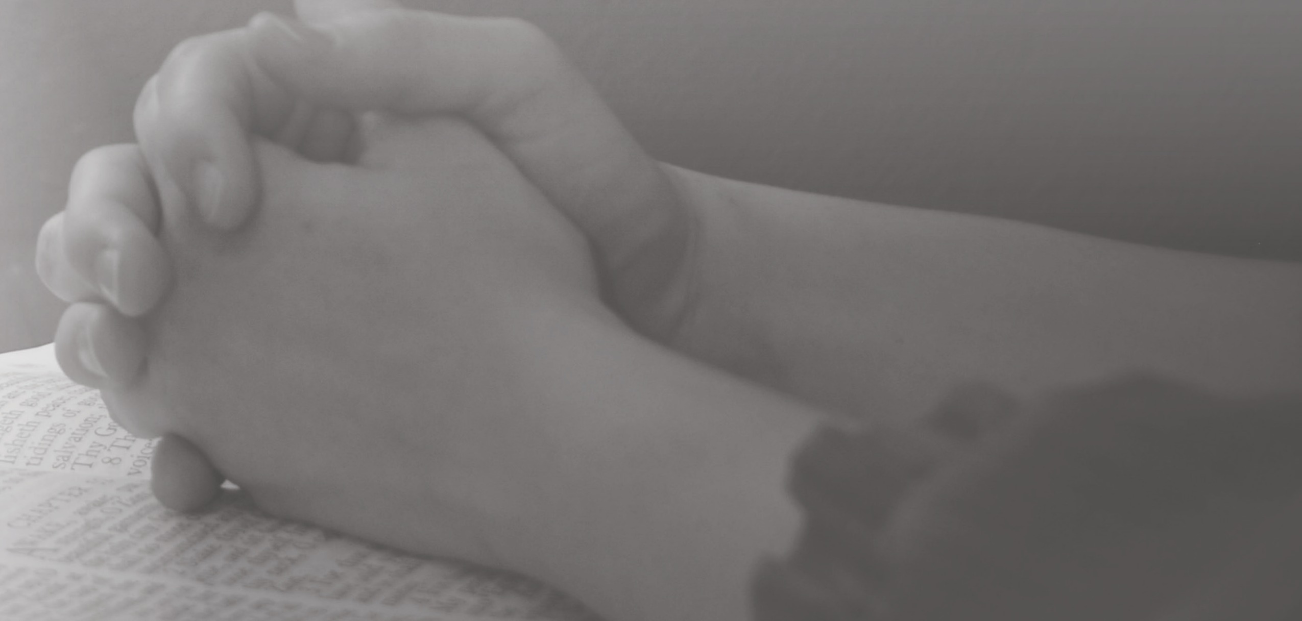 Clasped hands resting on an open Bible