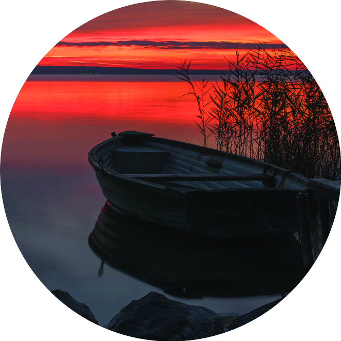 A rowboat silhouetted against a vivid red sunset