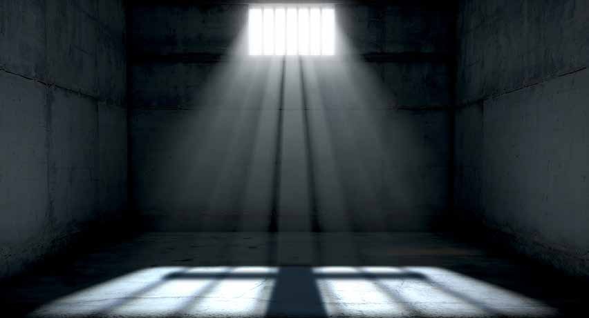 Daylight entering a dark prison cell through a barred window