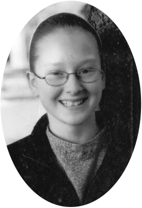 A smiling young woman wearing glasses beside a tree.