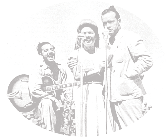 Three gospel performers singing and playing guitar at microphones