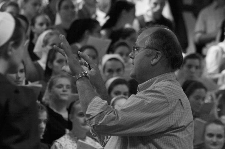 A man directing a seated choir