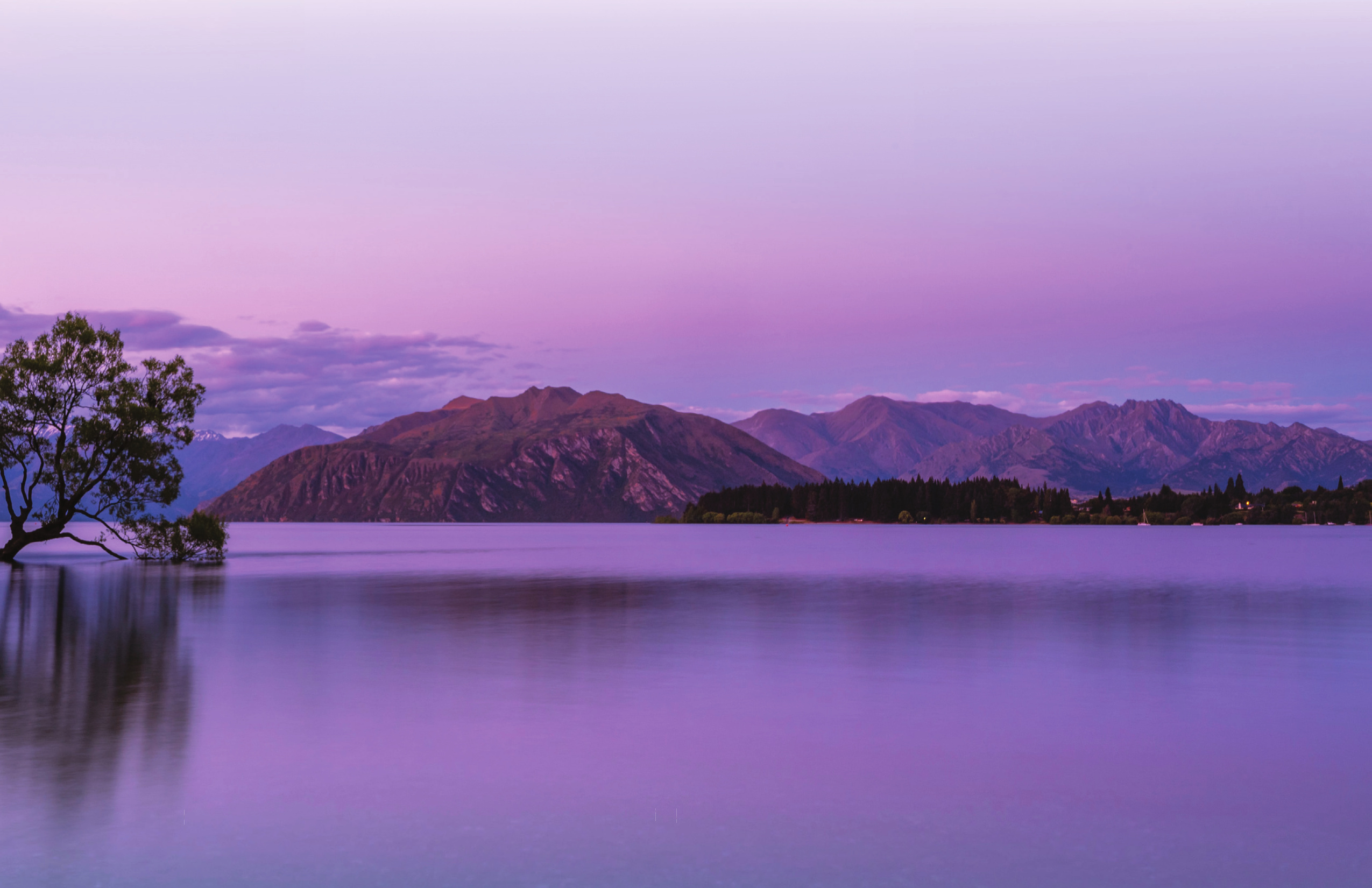 Mountains reflected in a calm lake beneath a purple sky